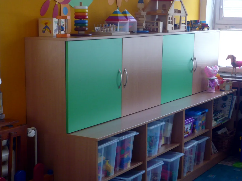 Úložná stěna ve třídě mateřské školy s barevnými dvířky a boxy